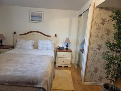 a bedroom with a bed and a night stand with a lamp at L ' Arlequin Suite et logement in Vaudreuil-Dorion