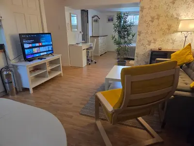 a living room with a television and a chair at L ' Arlequin Suite et logement in Vaudreuil-Dorion
