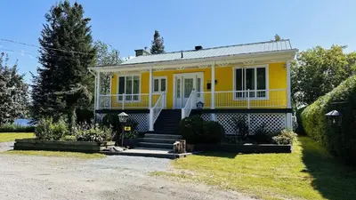 a yellow house with a front porch and stairs at Chalet KLS Lac D'Argent in Eastman