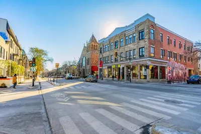 an empty city street with a crosswalk in front of buildings at Luminous and Stylish Renovated Apt in LePlateau in Montréal
