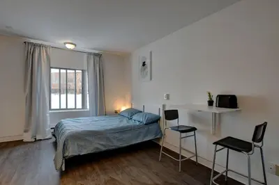 a bedroom with a bed and two chairs and a window at Laval stays 31 days minimum in Laval