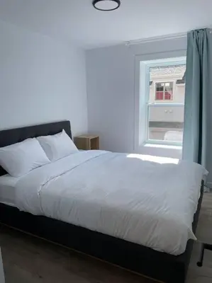 a bedroom with a white bed with a window at Bromont Lodge in Bromont