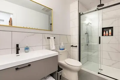 a white bathroom with a shower and a toilet at Bromont Lodge in Bromont