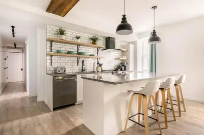 a white kitchen with a counter and stools at Bromont Lodge in Bromont