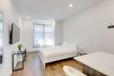 a white bedroom with a bed and a window at Le Mile End by M11 - Upscale Studio with Queen Bed in Montréal