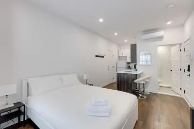 a white bedroom with a white bed and a bathroom at Le Mile End by M11 - Upscale Studio with Queen Bed in Montréal