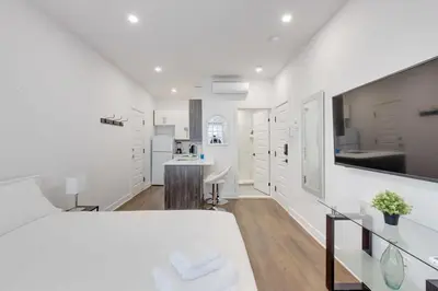 a white room with a bed and a kitchen at Le Mile End by M11 - Upscale Studio with Queen Bed in Montréal