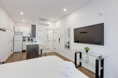 a kitchen with white walls and a large flat screen tv at Le Mile End by M11 - Upscale Studio with Queen Bed in Montréal