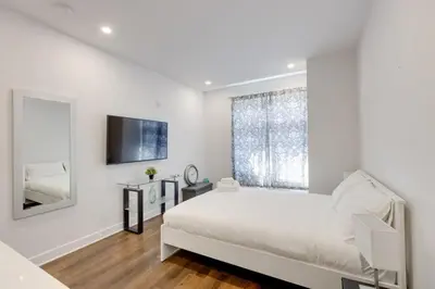a white bedroom with a bed and a large window at Le Mile End by M11 - Upscale Studio with Queen Bed in Montréal