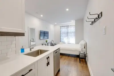a white kitchen with a sink and a bed at Le Mile End by M11 - Upscale Studio with Queen Bed in Montréal