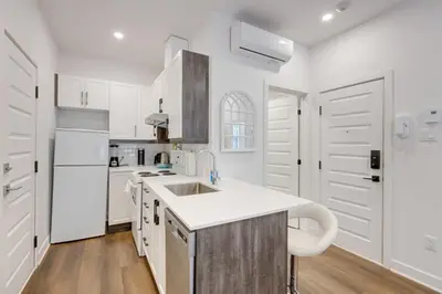 a white kitchen with white cabinets and a sink at Le Mile End by M11 - Upscale Studio with Queen Bed in Montréal