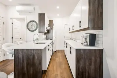 a kitchen with white cabinets and a clock on the wall at Le Mile End by M11 - Modern 1 BDR Unit with Sofa Bed in Montréal