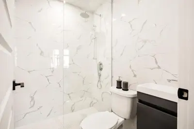 a white bathroom with a toilet and a shower at Le Mile End by M11 - Modern 1 BDR Unit with Sofa Bed in Montréal