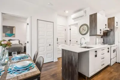 a kitchen with white cabinets and a table with chairs at Le Mile End by M11 - Modern 1 BDR Unit with Sofa Bed in Montréal