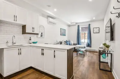 a kitchen with white cabinets and a wooden floor at Le Mile End by M11 - Upscale Comfy Studio in Montréal