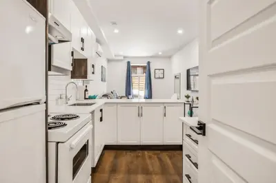 a white kitchen with white appliances and wooden floors at Le Mile End by M11 - Upscale Comfy Studio in Montréal