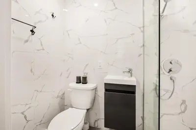 a white bathroom with a toilet and a sink at Le Mile End by M11 - Upscale Comfy Studio in Montréal