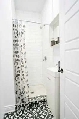 a bathroom with a shower with a black and white floor at Le Mile End by M11 - Modern Studio in Montréal