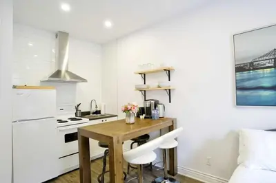 a small kitchen with a wooden table and white appliances at Le Mile End by M11 - Modern Studio in Montréal