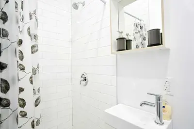 a white bathroom with a sink and a shower at Le Mile End by M11 - Modern Studio in Montréal