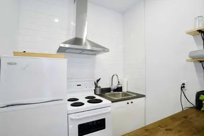 a white kitchen with a stove and a sink at Le Mile End by M11 - Modern Studio in Montréal