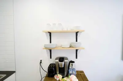 a shelf with plates and cups on a table at Le Mile End by M11 - Modern Studio in Montréal