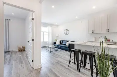 a white kitchen and living room with a blue couch at Le Mile End by M11 - Upscale & Spacious 1BDR with King Bed in Montréal
