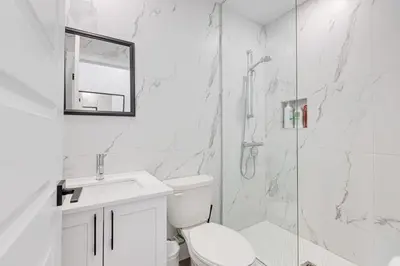 a white bathroom with a toilet and a shower at Le Mile End by M11 - Upscale & Spacious 1BDR with King Bed in Montréal