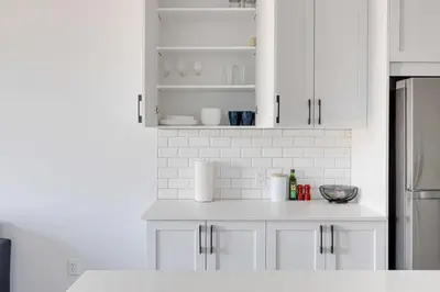 a white kitchen with white cabinets and a counter top at Le Mile End by M11 - Upscale & Spacious 1BDR with King Bed in Montréal