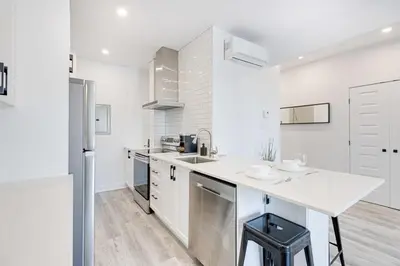 a white kitchen with a sink and a refrigerator at Le Mile End by M11 - Upscale & Spacious 1BDR with King Bed in Montréal