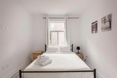 a bedroom with a bed with white sheets and a window at Le Mile End by M11 - Modern 2BDR with Sofa Bed in Montréal
