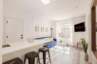 a kitchen and living room with a counter and stools at Le Mile End by M11 - Modern 2BDR with Sofa Bed in Montréal