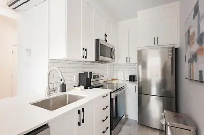 a kitchen with white cabinets and a stainless steel refrigerator at Le Mile End by M11 - Modern 2BDR with Sofa Bed in Montréal