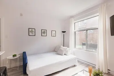 a white bedroom with a bed and a window at Le Mile End by M11 - Modern 2BDR with Sofa Bed in Montréal