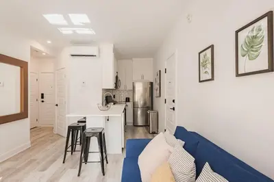 a living room with a blue couch and a kitchen at Le Mile End by M11 - Modern 2BDR with Sofa Bed in Montréal