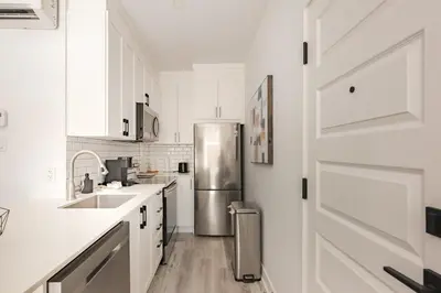 a kitchen with white cabinets and a stainless steel refrigerator at Le Mile End by M11 - Spacious 2BDR Unit with Sofa Bed in Montréal