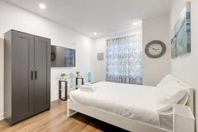 a white bedroom with a bed and a clock on the wall at Le Mile End by M11 - Modern & Comfy Studio in Montréal