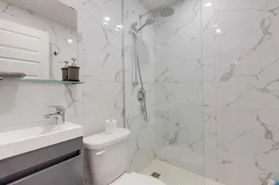 a white bathroom with a shower and a toilet at Le Mile End by M11 - Modern & Comfy Studio in Montréal