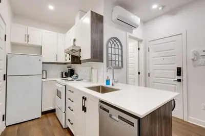 a white kitchen with a sink and a refrigerator at Le Mile End by M11 - Modern & Comfy Studio in Montréal