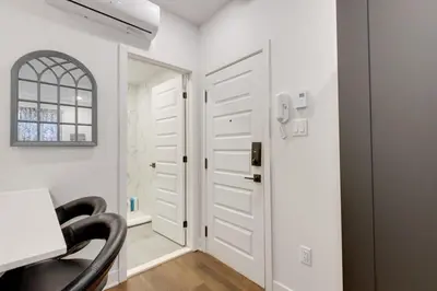 a white hallway with a black chair and a door at Le Mile End by M11 - Modern & Comfy Studio in Montréal