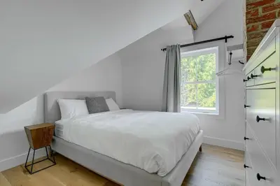 a white bedroom with a bed and a window at Maison ancestrale complètement rénovée 4 chambres in Bromont