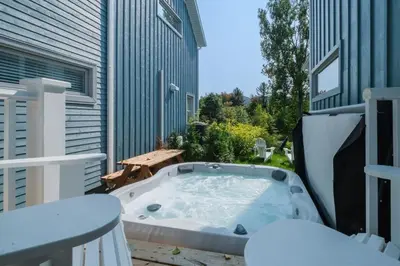 a jacuzzi tub on a patio with a table at Maison ancestrale complètement rénovée 4 chambres in Bromont
