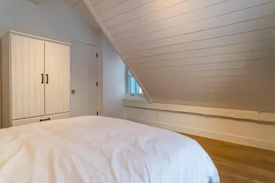 a bedroom with a white bed and a window at Maison 3 chambres à coucher vue sur la montagne in Bromont