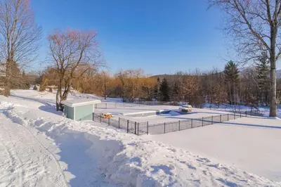 a snow covered park with a fountain in the middle at Maison 3 chambres à coucher vue sur la montagne in Bromont