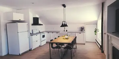 a kitchen with a wooden table and white appliances at Villa de Brome in Lac-Brome