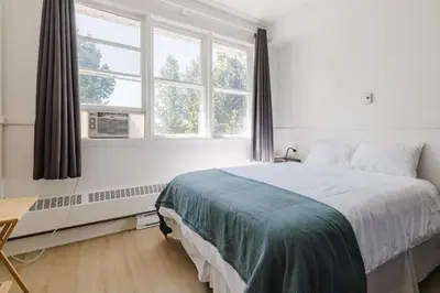 a bedroom with a large bed and two windows at Villa de Brome in Lac-Brome