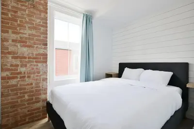 a bedroom with a white bed and a brick wall at Bromont Lodge 837 shefford suite 200 in Bromont