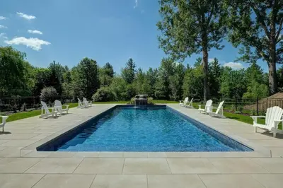 a swimming pool with white chairs and a swimming poolvisor at condo 3 chambres vue sur la montagne 837-202 in Bromont