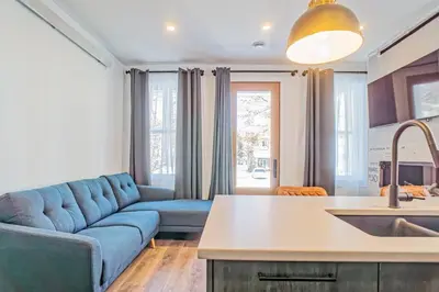 a living room with a blue couch and a kitchen at 201 Condo au rez de chaussée , au coeur de Bromont in Bromont