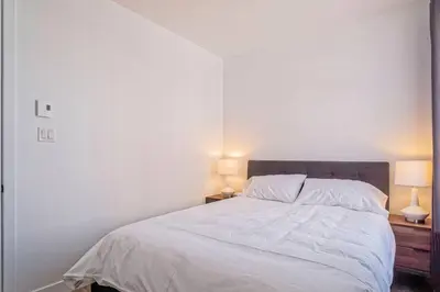 a bedroom with a white bed with two lamps at 201 Condo au rez de chaussée , au coeur de Bromont in Bromont